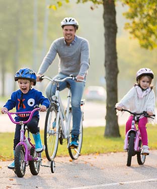Pappa och två barn cyklar i Katrineholm.