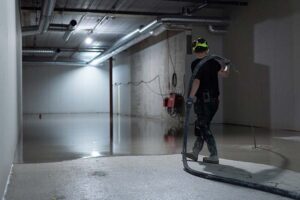 Medarbetare på Jönköpings Industrigolv arbetar med maskin på golv i tom rum.