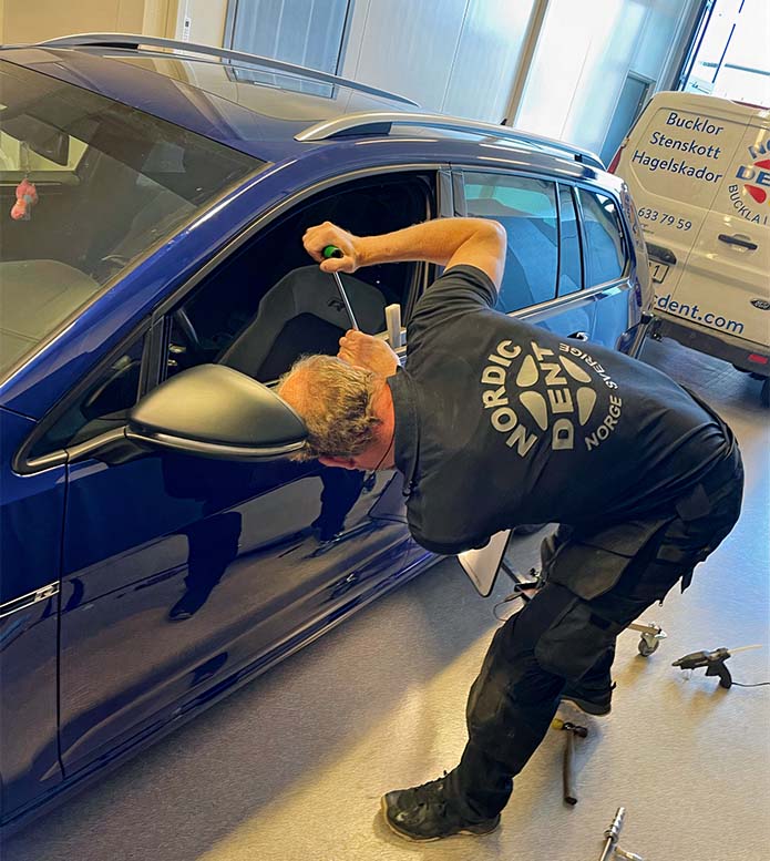 Mekaniker på Nordic Dent reparerar en buckla på en bil i verkstaden.